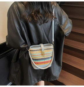 Detail of colorful rainbow woven straw bucket bag with blue leather trim and metal clasp