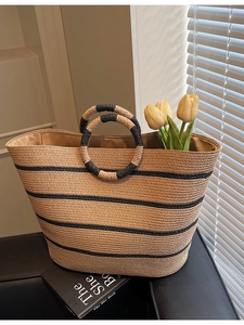Handwoven straw tote bag with black stripes and circular handles for summer beach vacations