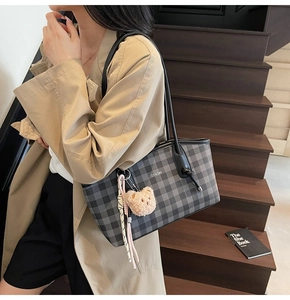 Fashionable checkerboard tote bag with bear charm shown on a casual model outfit