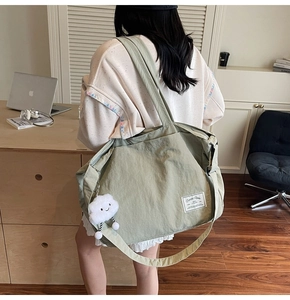 Détail du sac de voyage en toile vert sauge avec bandoulière large et pendentif nuage