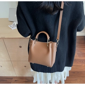 Brown litchi leather bucket bag shown on a model from a back-side perspective