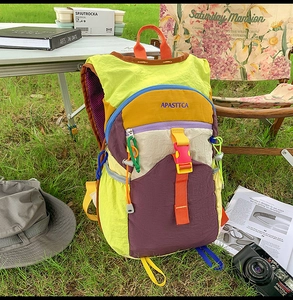 Détail du sac à dos en nylon multicolore avec boucle orange réglable sur l'herbe verte