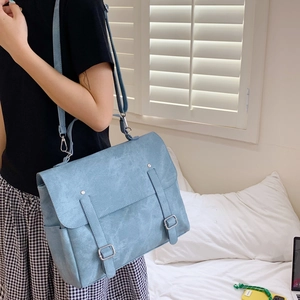 Detail of light blue vintage college style backpack with matte leather and metal buckles