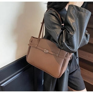Detail of dark brown tote bag with litchi texture and metal buckle on long shoulder strap