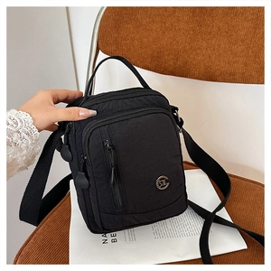 Close-up of black nylon crossbody bag featuring multiple zippers and adjustable strap