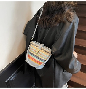 Detail of colorful woven straw bucket bag with blue leather strap and gold metal lock