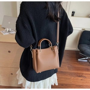 Litchi texture caramel leather bucket bag with gold hardware shown in lifestyle setting