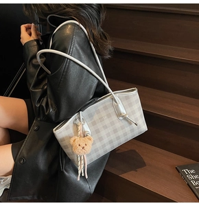 Detail of grey checkerboard tote bag with silver strap and plush bear charm decoration
