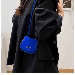 Blue mini saddle bag with golden orin print worn over a classic black blazer