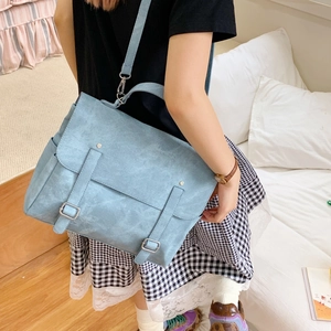 Detail of light blue vintage satchel with matte finish and silver metal buckle closures