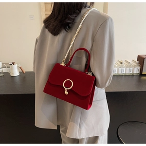 Detail view of red velvet crossbody bag with gold ring hardware and pearl chain strap