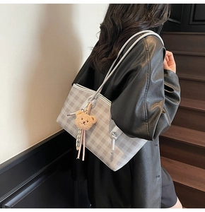 Detail of grey gingham tote bag with thin straps and cute plush bear charm on model