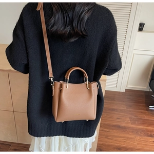 Brown leather bucket bag with silver metal handle hardware shown on a female model