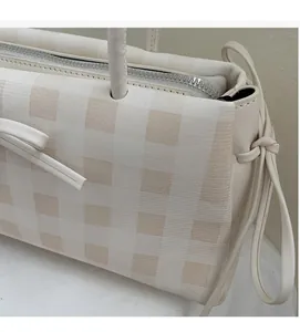 Detail of light beige plaid fabric texture with silver zipper and leather shoulder strap