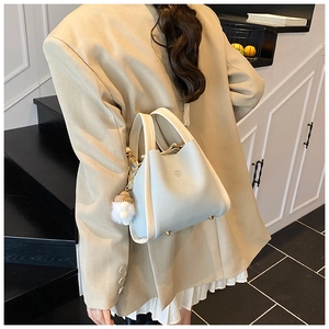 Detail of light blue lychee leather bucket bag with cream handle and plush pompom charm