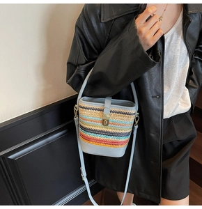 Detail of colorful woven straw bucket bag with blue leather trim and golden metal clasp