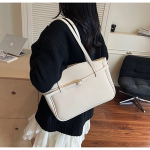Detail of off-white lychee texture tote bag with metal eyelet strap on a shoulder