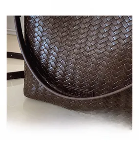 Détail rapproché du sac seau en cuir tressé marron foncé avec étiquette de logo