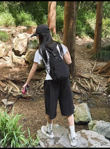 Detail of durable black nylon crossbody bag with metal zippers shown in outdoor setting