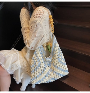 Detail of hand-woven crochet tote bag with blue-white texture and yellow wooden beads