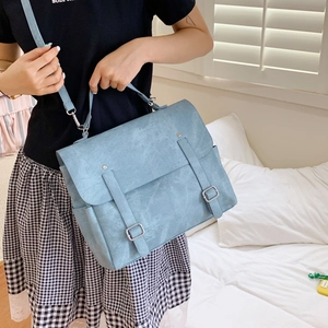 Close-up of light blue vintage backpack showing matte texture and metal buckle straps