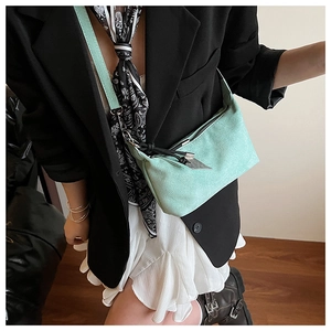 Detail view of mint green suede shoulder bag with silver triangle charm and black zipper