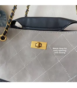 Close-up of golden metal twist lock and quilted diamond pattern on grey crossbody bag