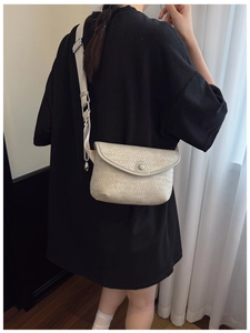 Détail du sac à bandoulière beige tissé avec texture à damier et large sangle réglable