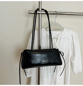 Gros plan du sac sous l'aisselle en cuir noir froissé avec logo métallique argenté