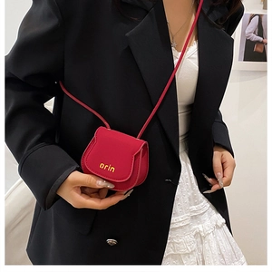 Close-up of a mini red leather crossbody bag featuring the yellow orin logo on the front