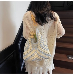 Detailed look at woven crochet shoulder bag with blue patterns and yellow wooden beads