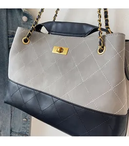 Detail of quilted stitching on grey suede and black leather patchwork shoulder bag