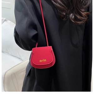 Close-up of red mini cat-ear crossbody bag with orin logo on a black suit background