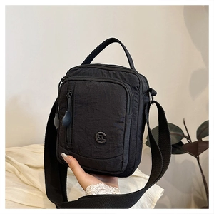 Handheld view showing compact size of black multi-pocket nylon crossbody bag