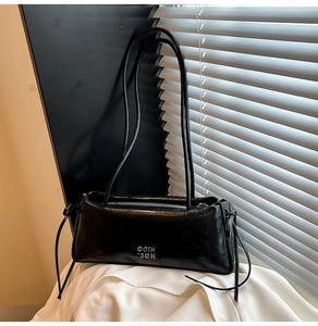 Détail du sac bandoulière en similicuir noir brillant avec logo argenté et doubles anses