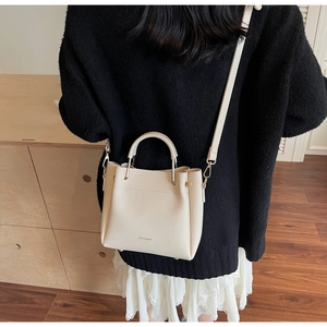Chic beige textured bucket bag shown as a crossbody and handbag on a model's outfit