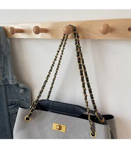 Detail of light gray quilted shoulder bag with golden twist lock and chain strap