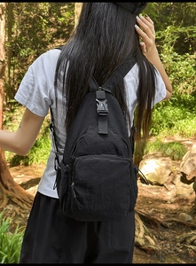 Detail of black waterproof nylon crossbody bag with multi-zipper pockets and buckle in forest