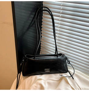 Détail du sac bandoulière en cuir noir brillant avec logo argenté sur soie blanche