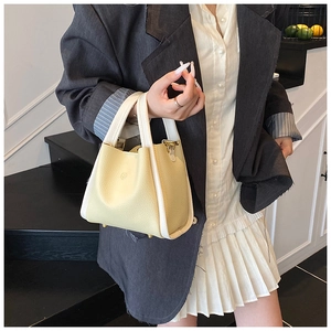 Detail of yellow bucket bag with contrast trim and logo paired with chic office attire