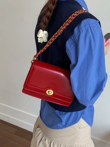 Fashionable red flap crossbody bag with gold chain strap and metal clasp closure