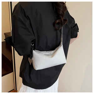 Detail of white baguette bag with a silver heart pendant on a stylish shoulder strap