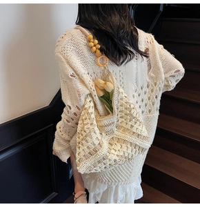 Detail of woven tote bag with yellow wooden beads on shoulder strap and hollow texture