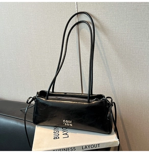 Détail du sac sous l'aisselle en cuir noir brillant avec des nœuds décoratifs
