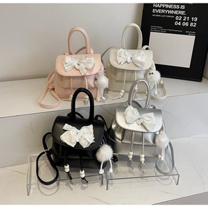 Detailed view of mini PU leather backpacks in four colors with lace bows and fur ball charms