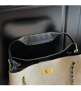 Detail of quilted texture, black leather handle and gold twist lock on stylish handbag
