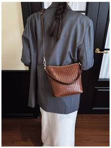 Détail du sac bandoulière tissé marron foncé avec logo en cuir sur une veste de costume