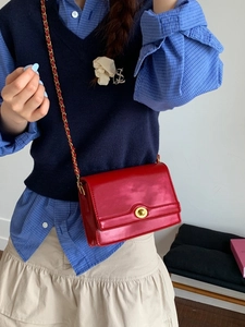 Fashionable red leather crossbody bag with gold chain strap and circular lock buckle