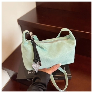 Close-up of mint green suede shoulder bag with silver zipper and heart charm detail