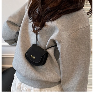 Detailed close-up of a mini black saddle bag worn by model featuring golden orin logo